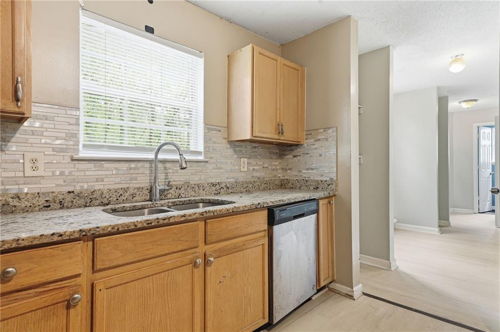 Kitchen with wood cabinets, granite counters, a tiled backsplash, and a window over the sink.