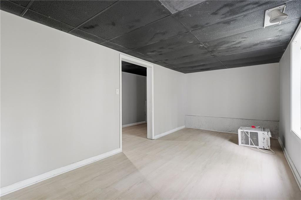 Empty room with a dark tiled ceiling, light flooring, and a window air-conditioning unit.