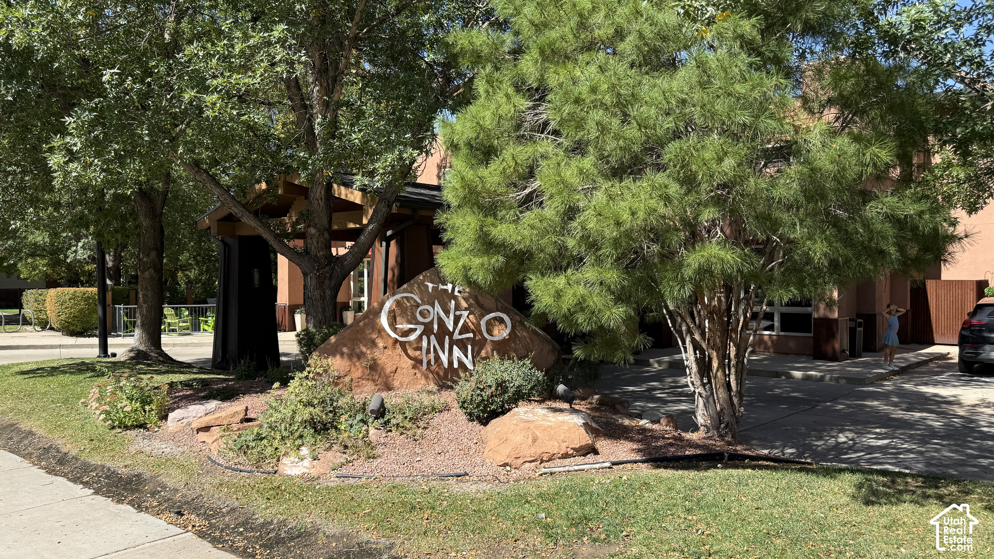 The Gonzo Inn entrance behind mature trees, with its name painted on a large rock sign.