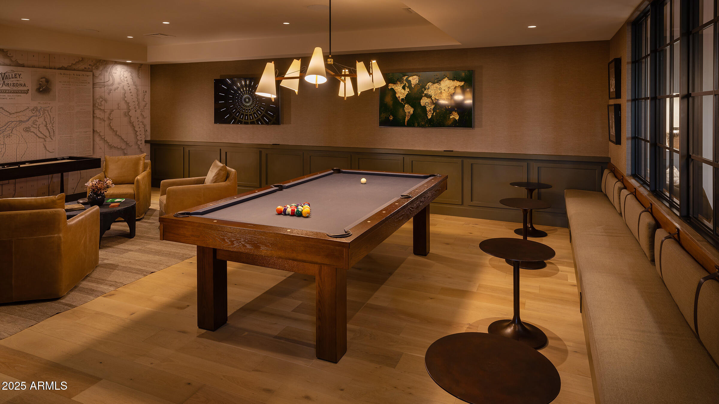 Furnished billiards lounge with a pool table, racked balls, upholstered seating, and a long window-side bench.