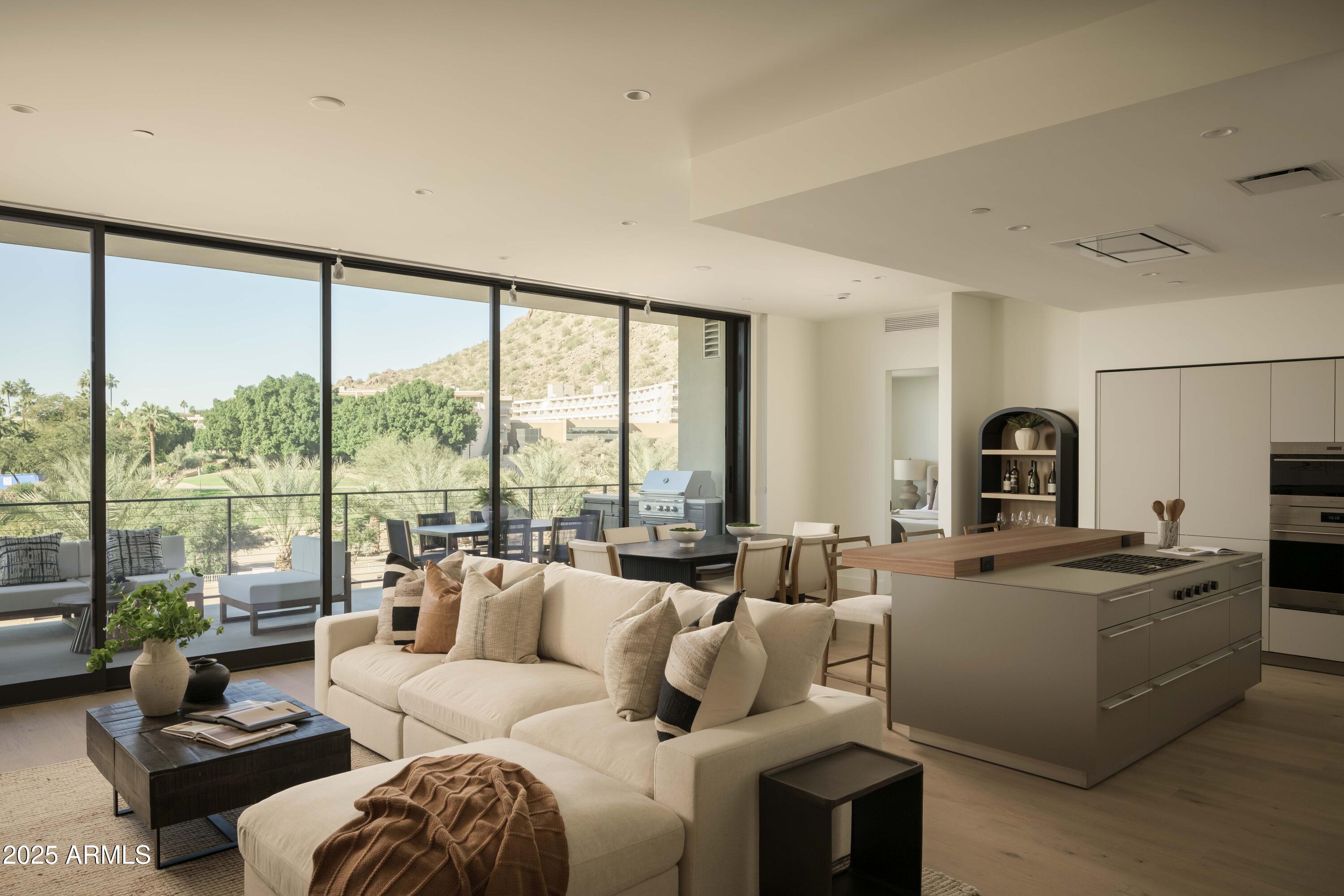 Open-plan living room and kitchen with a large island and sliding glass doors overlooking a desert hillside.