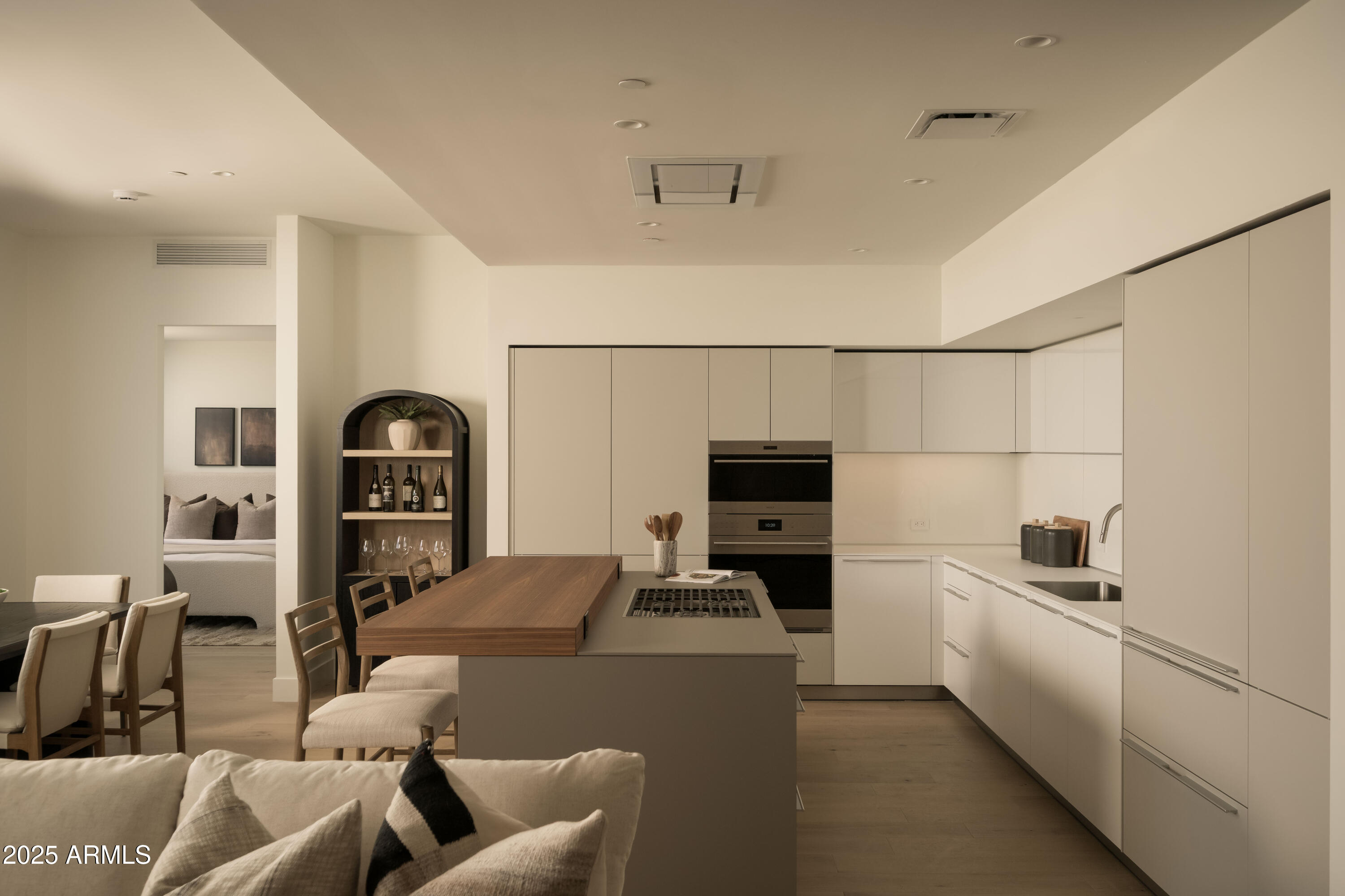 Open-plan kitchen with white cabinets, a large wood-topped island, and an adjacent dining area.