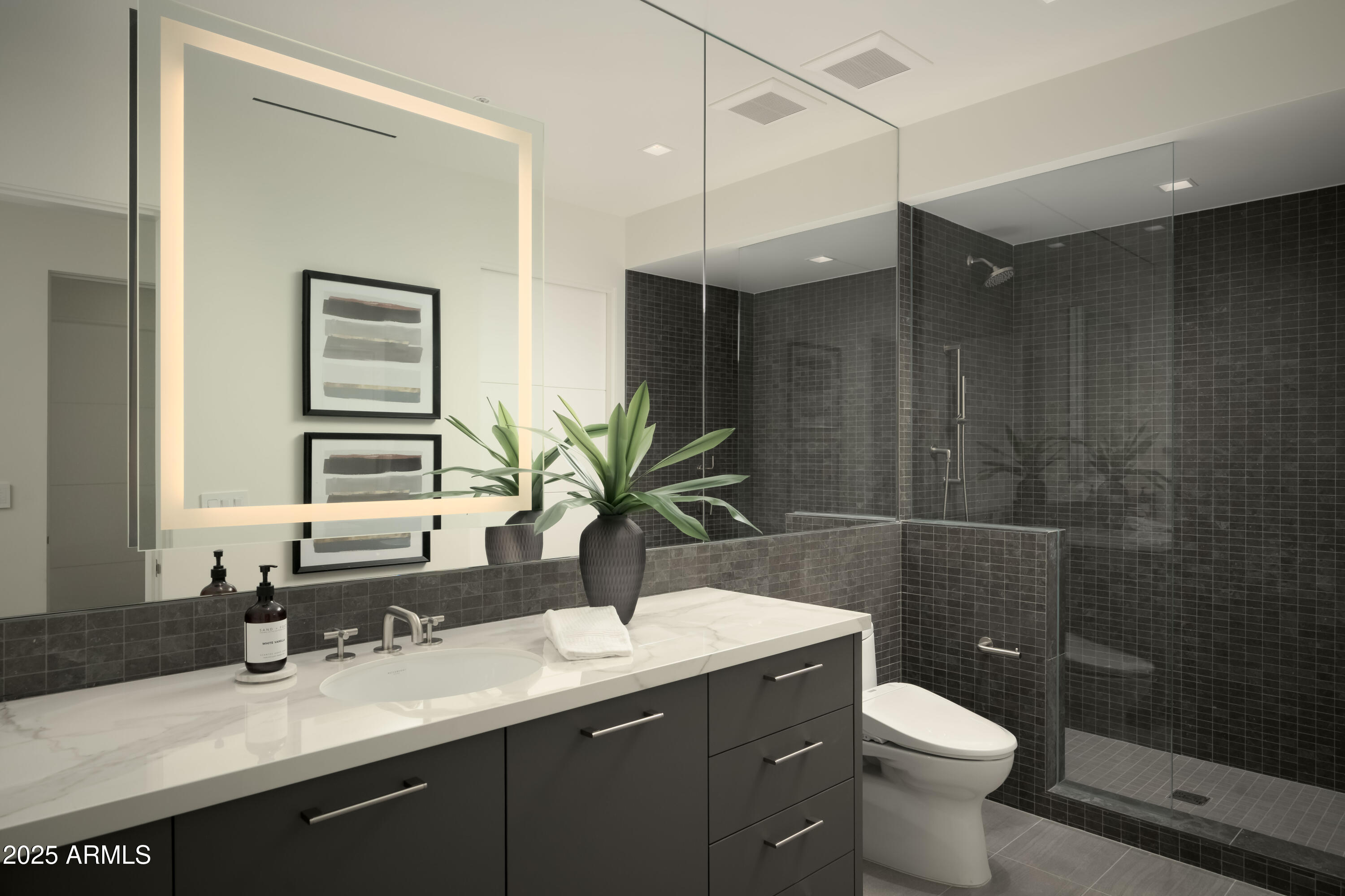 Modern bathroom with a marble vanity and glass-enclosed charcoal-tile shower.