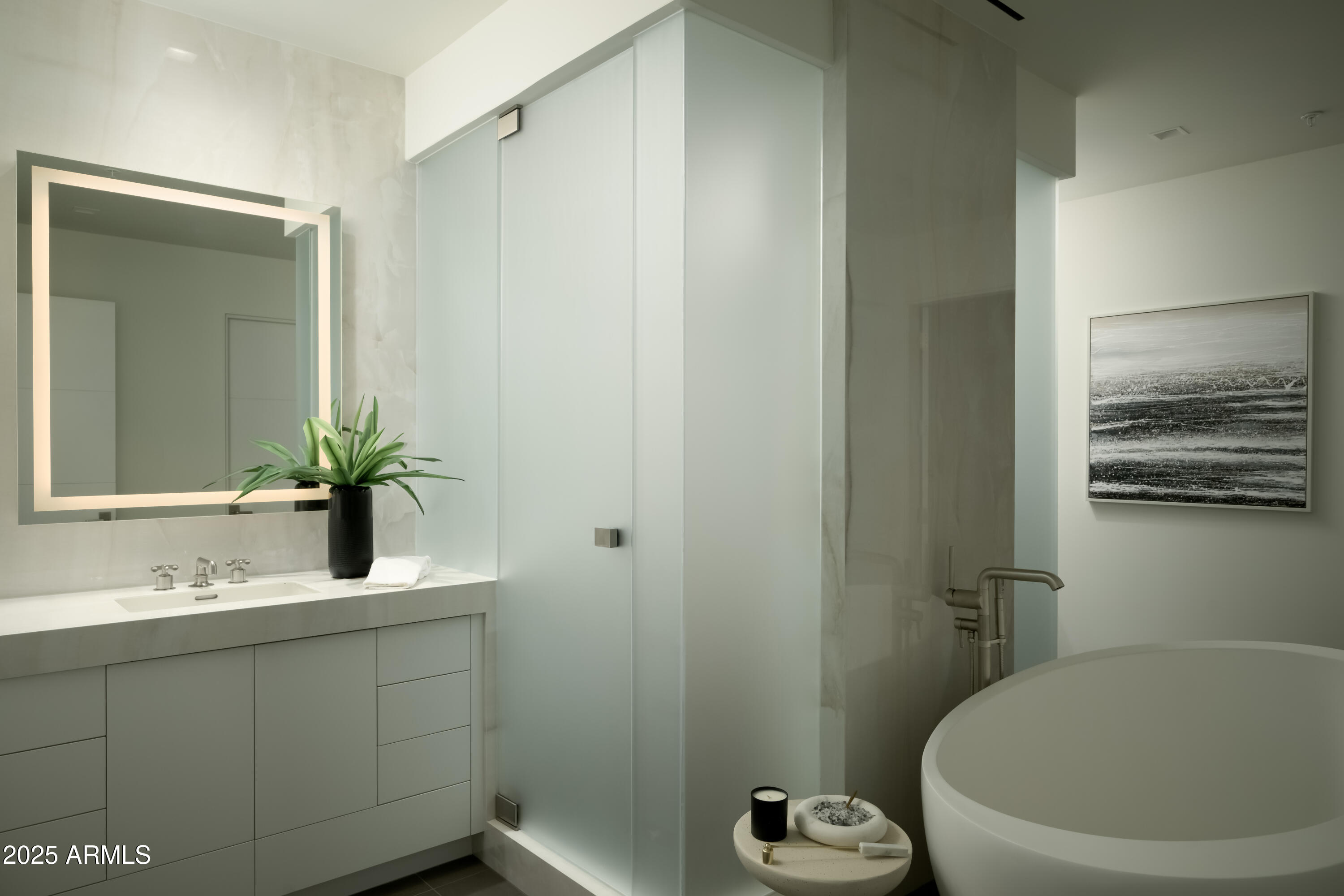 Modern bathroom with a glass shower, freestanding tub, and illuminated vanity mirror.