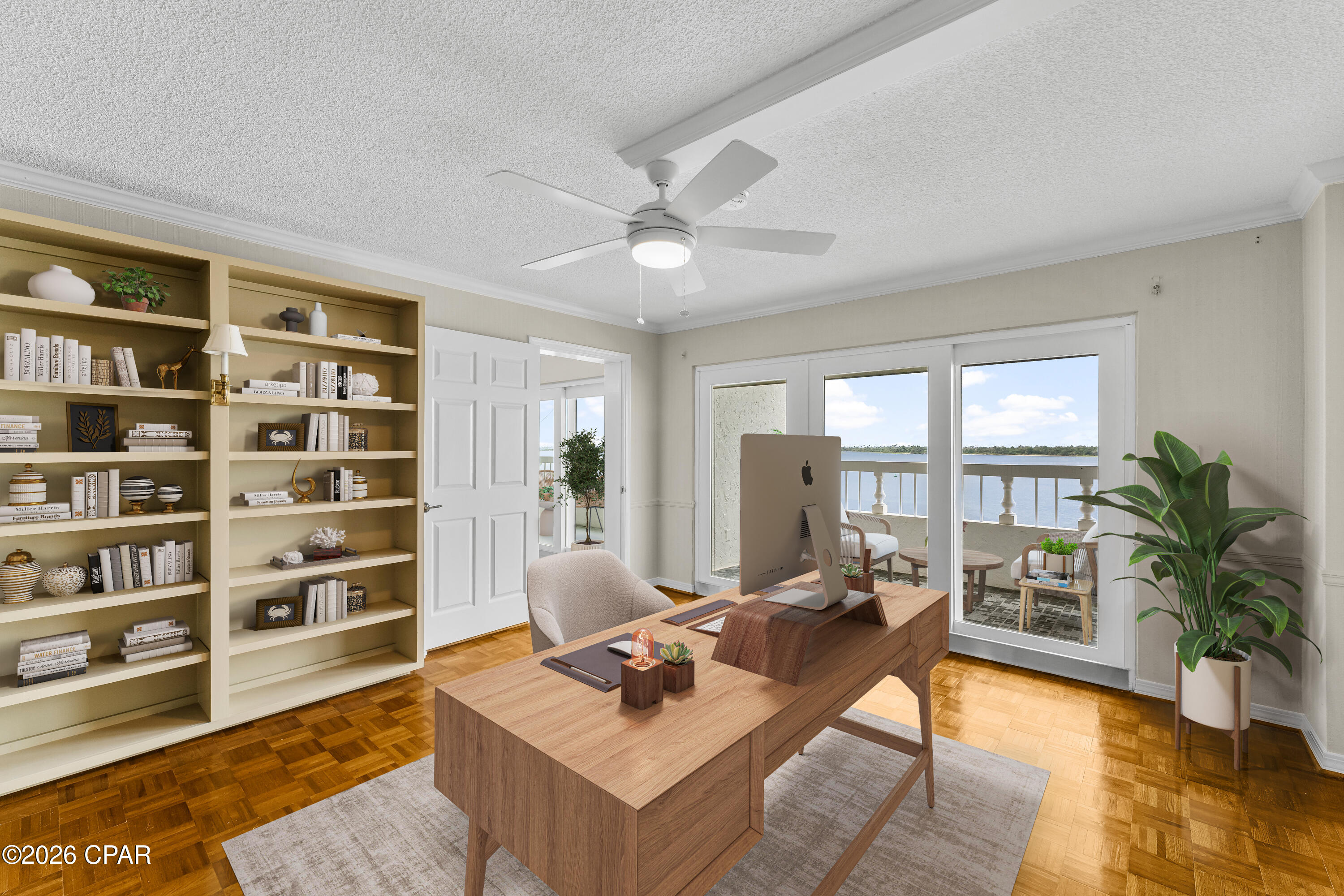 Staged home office with built-in bookshelves and a balcony overlooking the water.