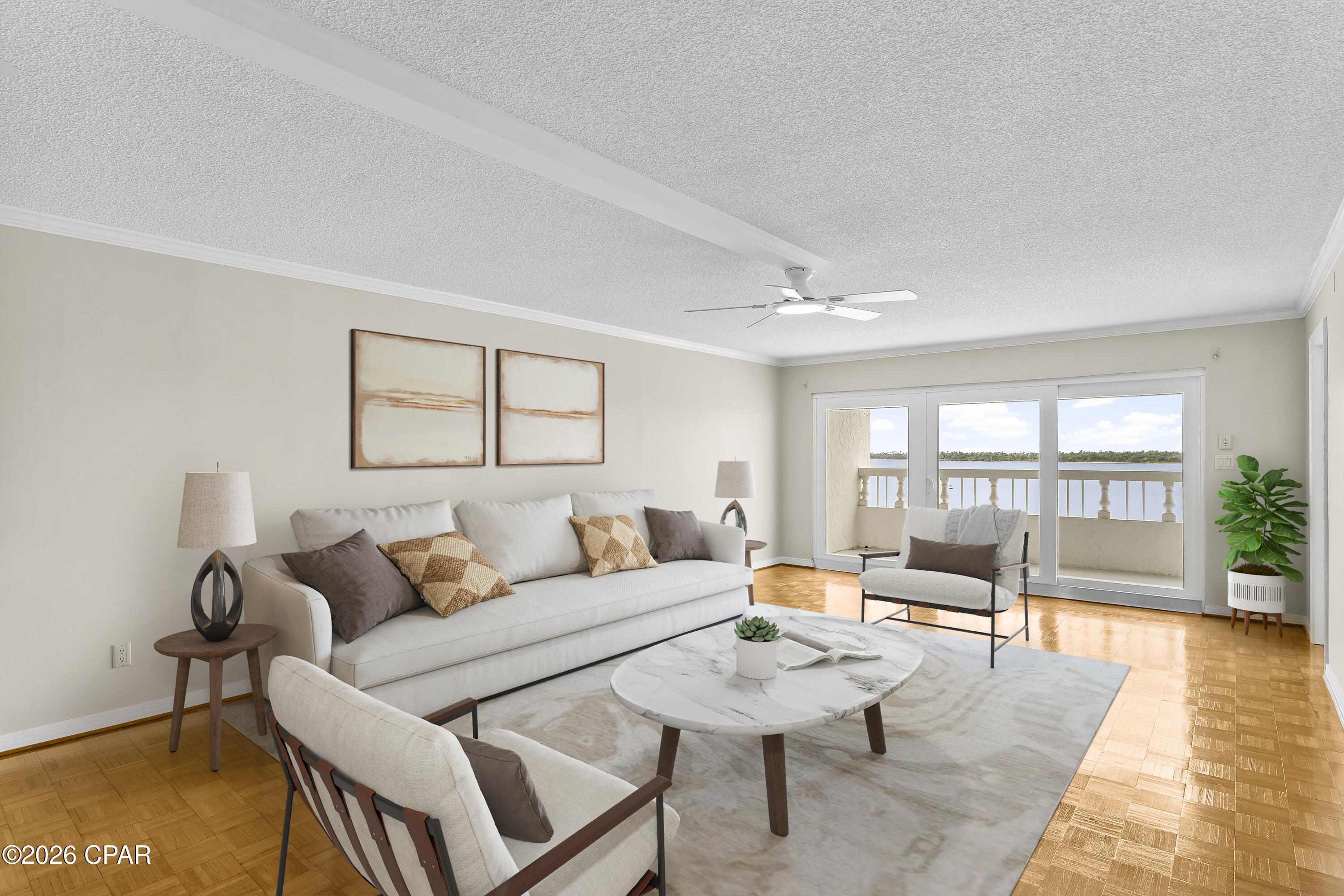 Living room with light furnishings, parquet flooring, and balcony doors overlooking the water.