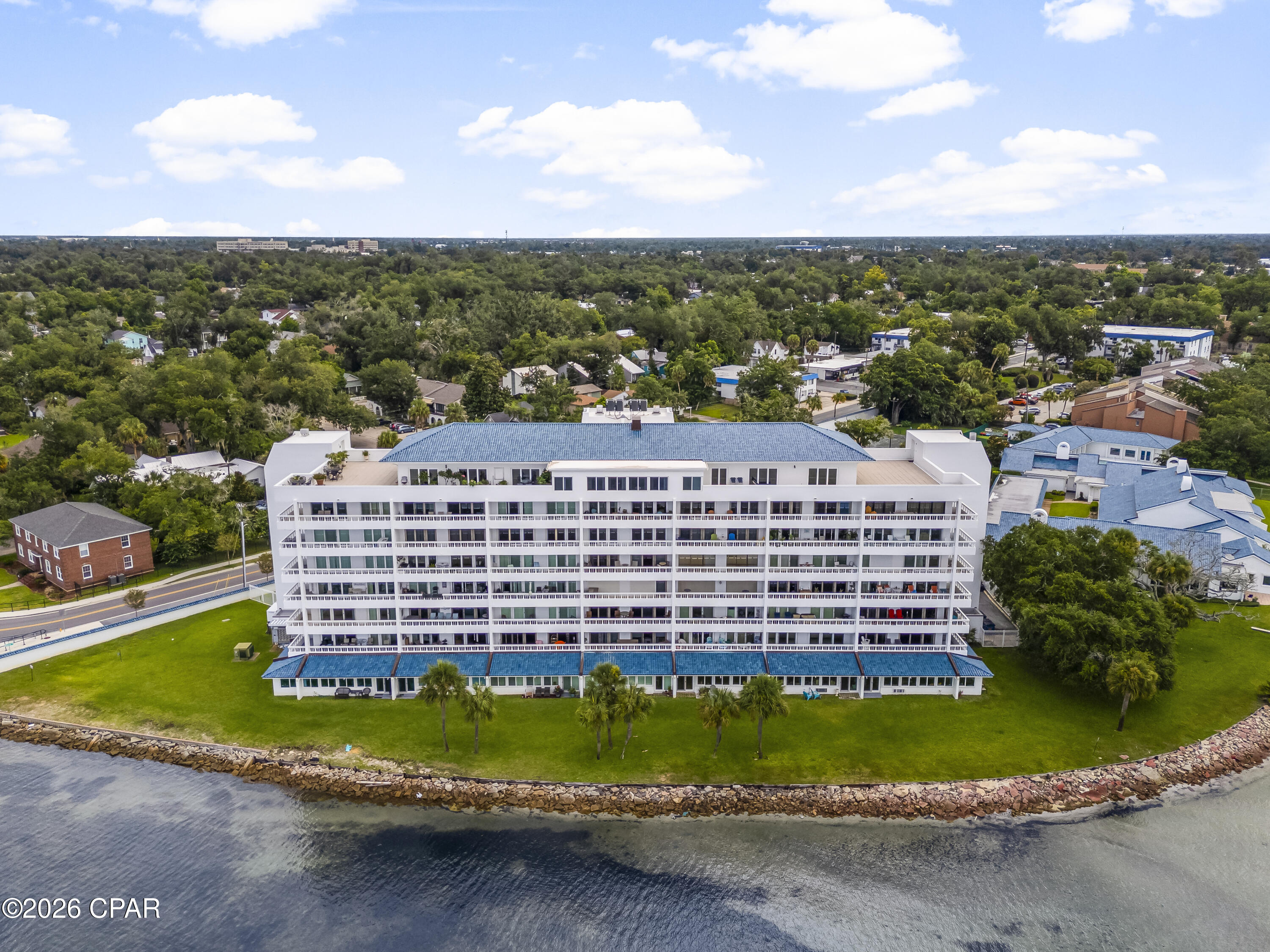 Waterfront condominium with blue roofs and a rocky shoreline, viewed from above.
