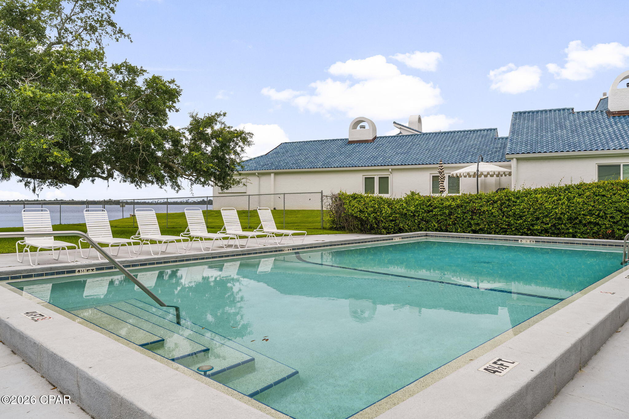 Outdoor swimming pool with submerged steps and white lounge chairs beside the water.