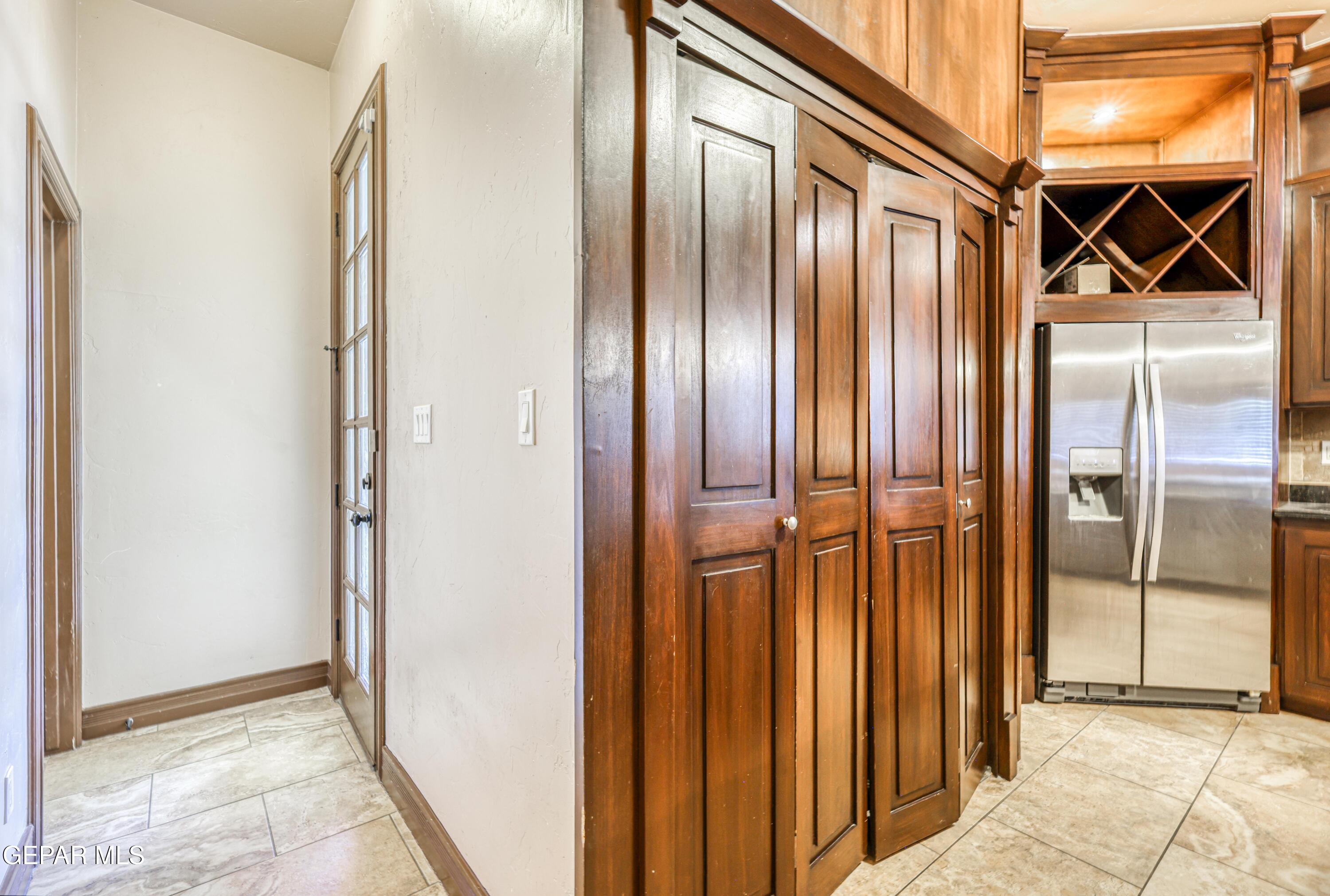 Kitchen with dark wood cabinetry, a stainless steel refrigerator, and light tiled flooring.