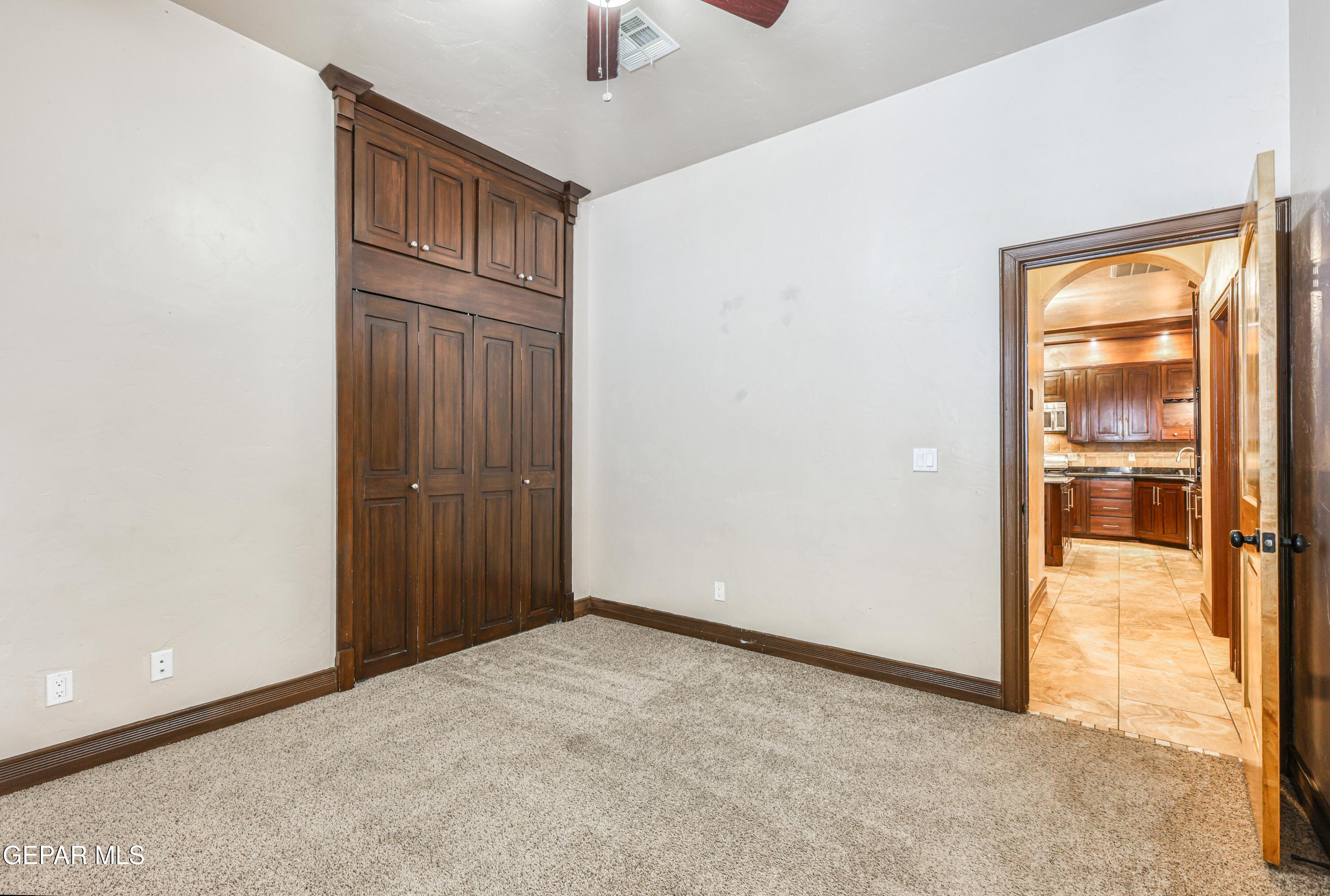 Unfurnished bedroom with a large built-in wood closet and a doorway to the kitchen.
