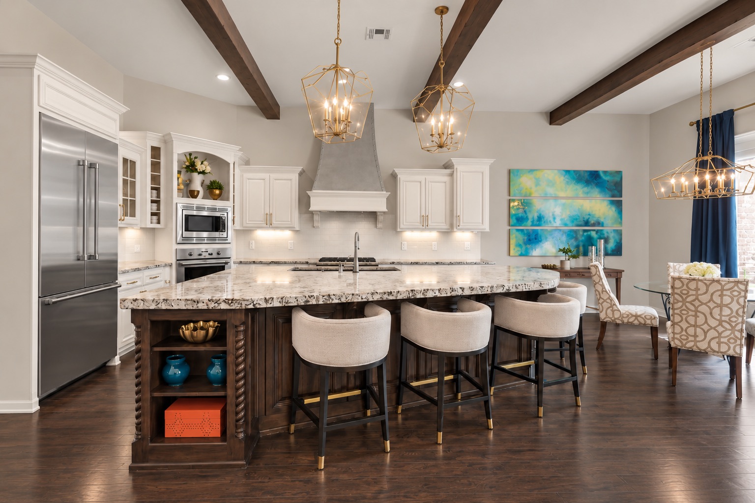 Kitchen with a large stone-topped island, white cabinetry, exposed beams, and brass pendant lights.