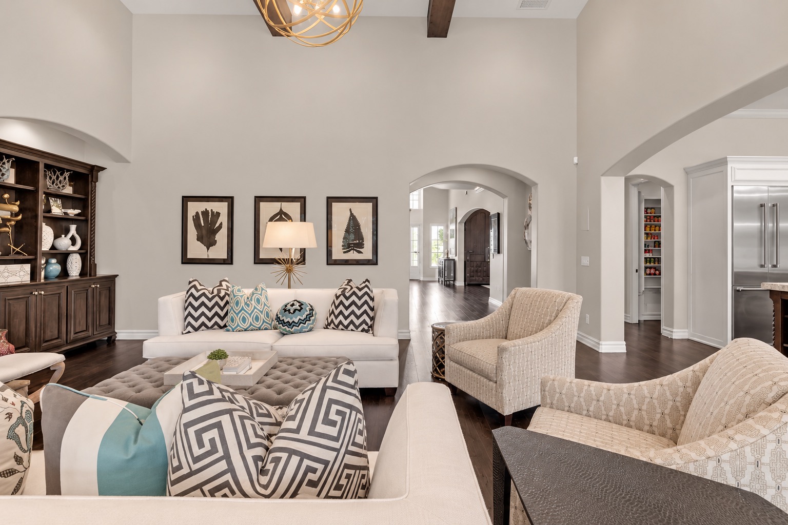 Living room with a white sofa and patterned pillows, upholstered armchairs, and arched openings.