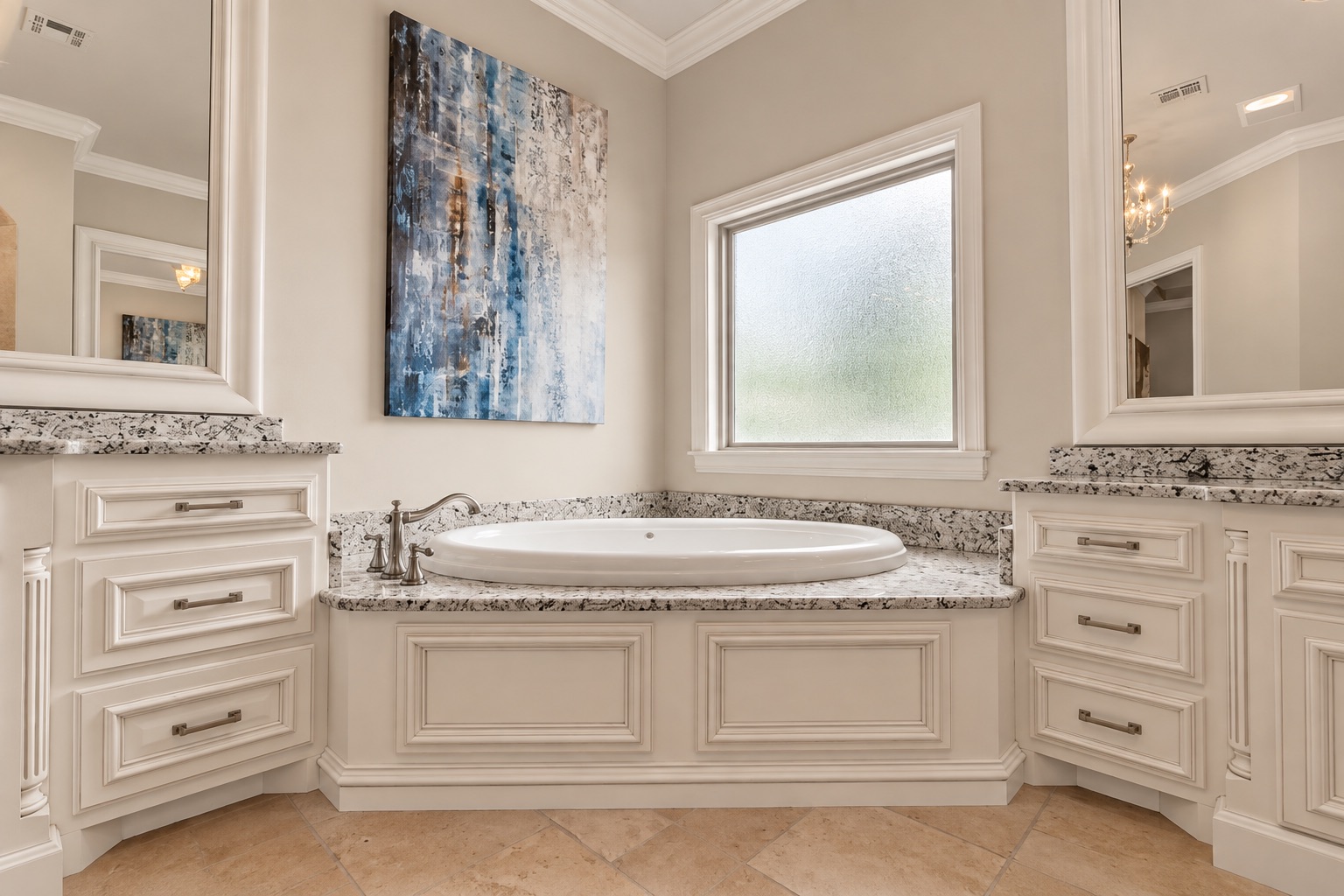 Bathroom with an oval soaking tub, granite surround, cream cabinetry, and blue abstract wall art.