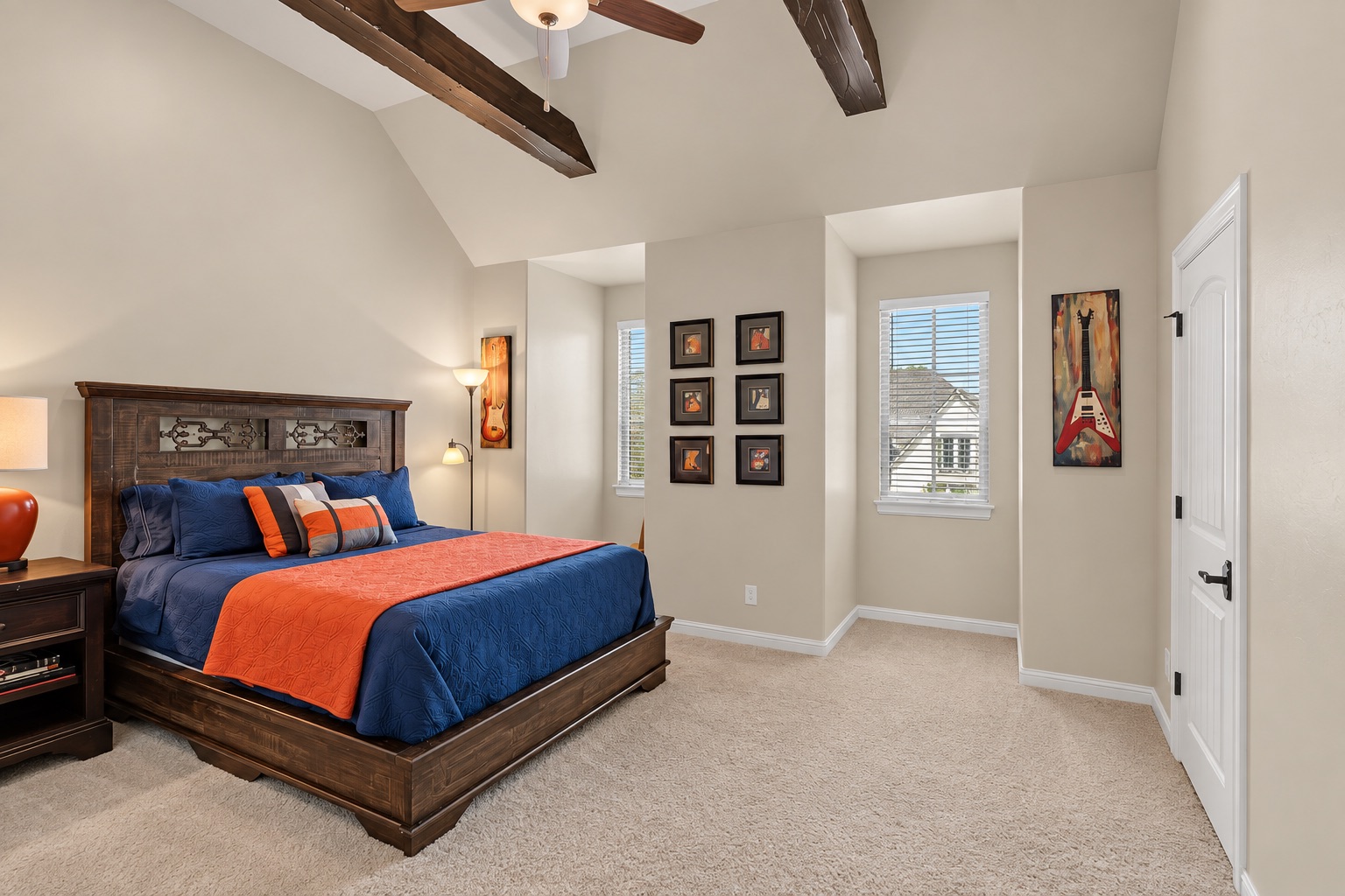 Bedroom with navy and orange bedding, exposed wood ceiling beams, and framed artwork.