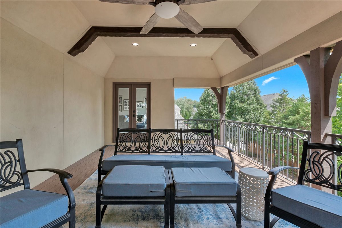 Covered patio with blue-cushioned seating, exposed beams, and views of trees.