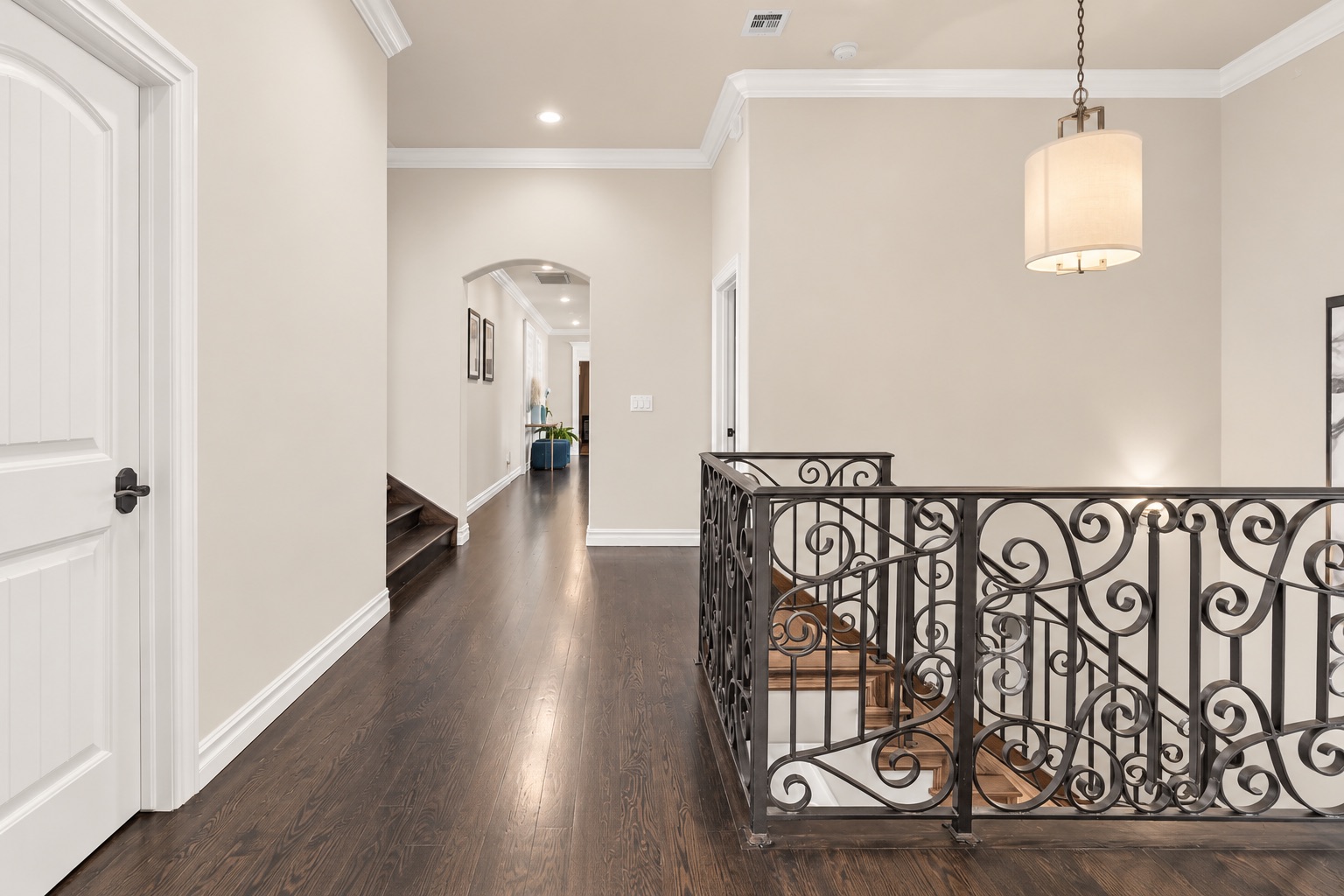 Upstairs landing with dark hardwood floors and an ornate wrought-iron stair railing.