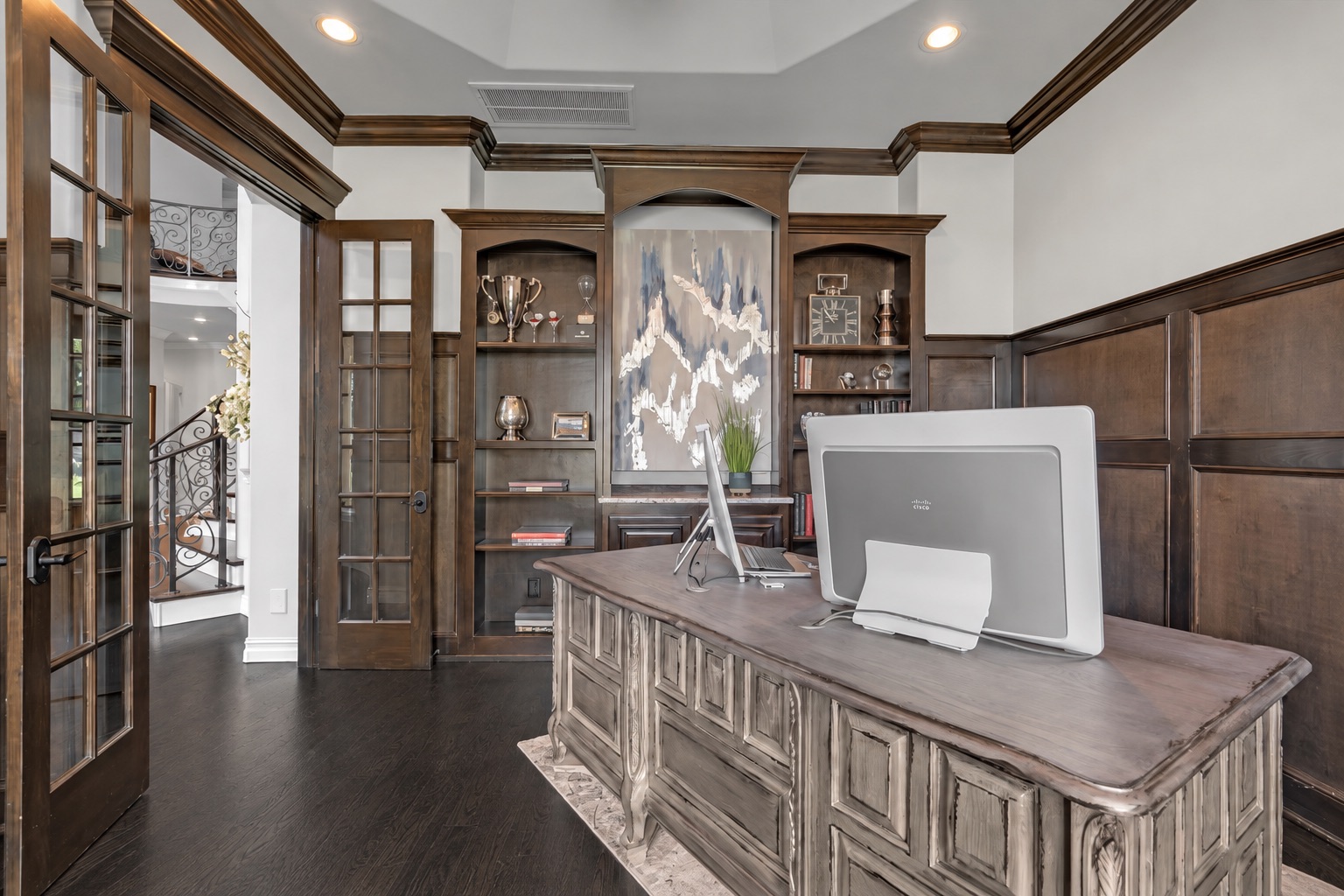 Home office with a carved wood desk and dark built-in shelves and paneling.