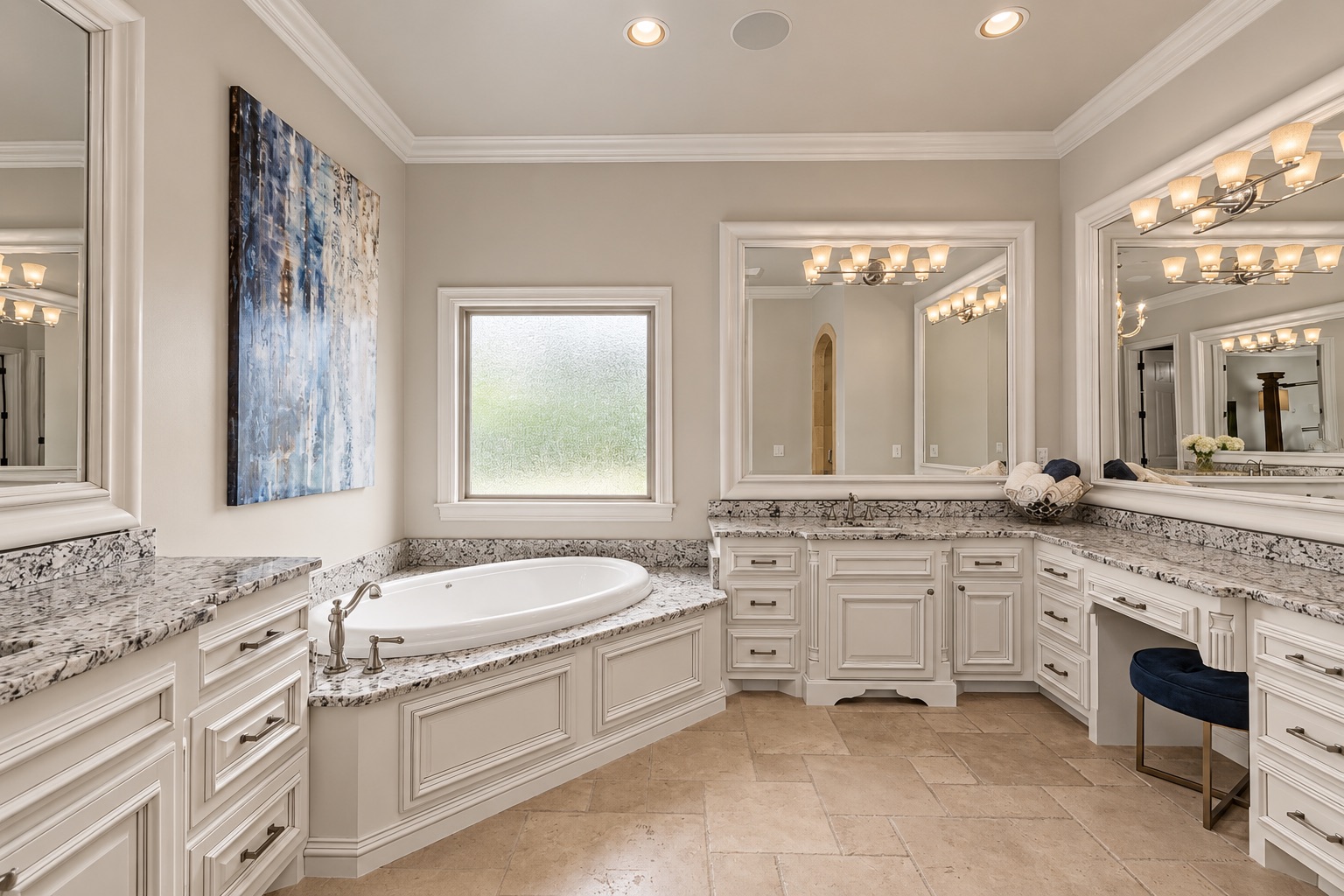 Spacious bathroom with a built-in soaking tub, white cabinetry, speckled stone counters, and large mirrors.