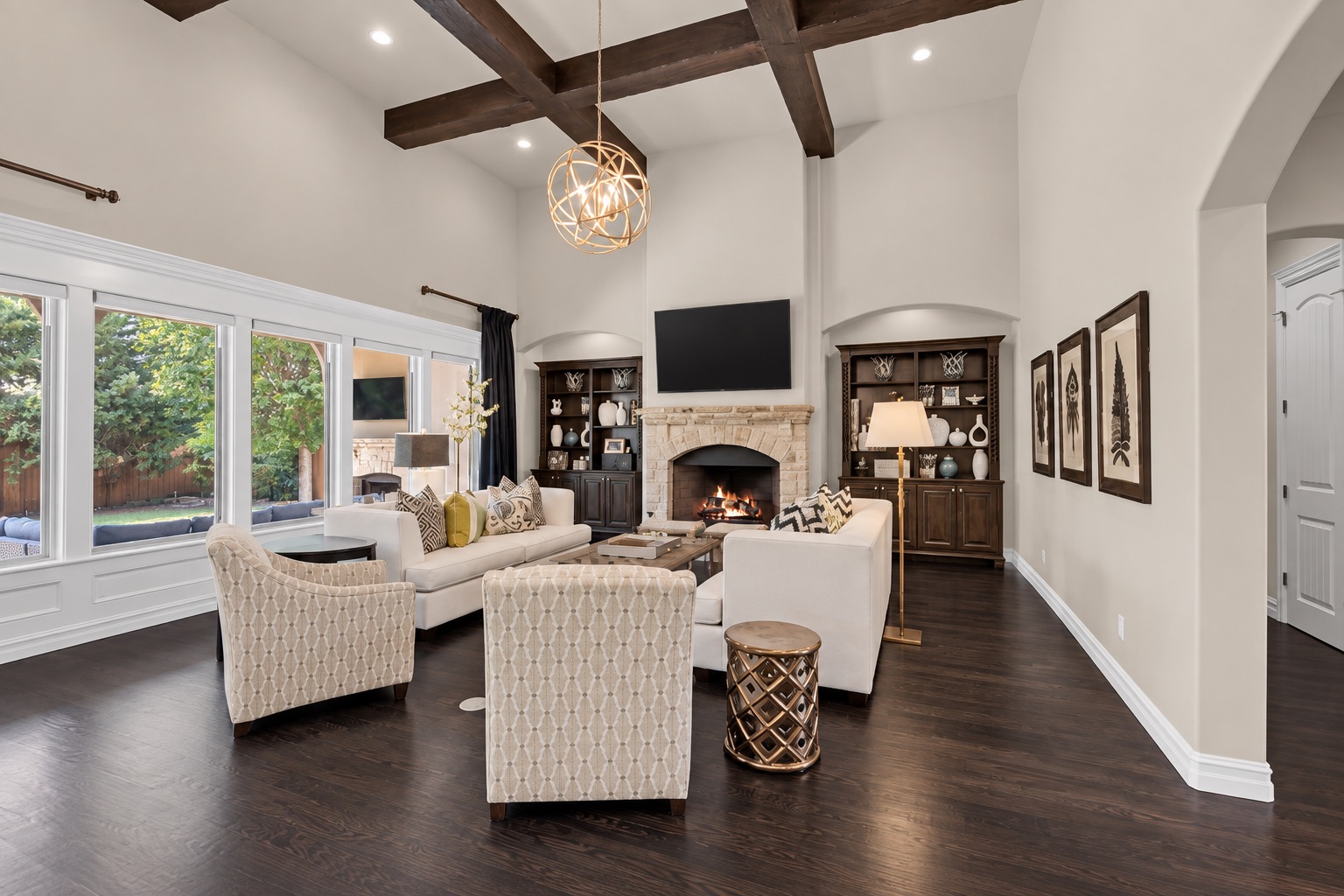 Living room with vaulted beamed ceiling, stone fireplace, built-in cabinets, and large windows.