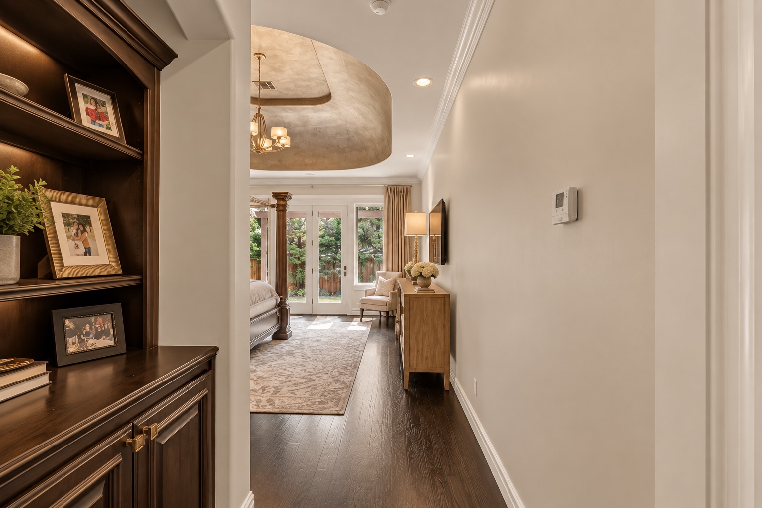 Hallway looking into a bedroom with dark built-in cabinetry, an arched ceiling, and garden-facing French doors.
