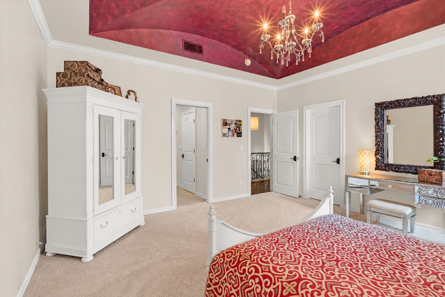 Bedroom with a red patterned bedspread and dramatic red recessed ceiling with chandelier