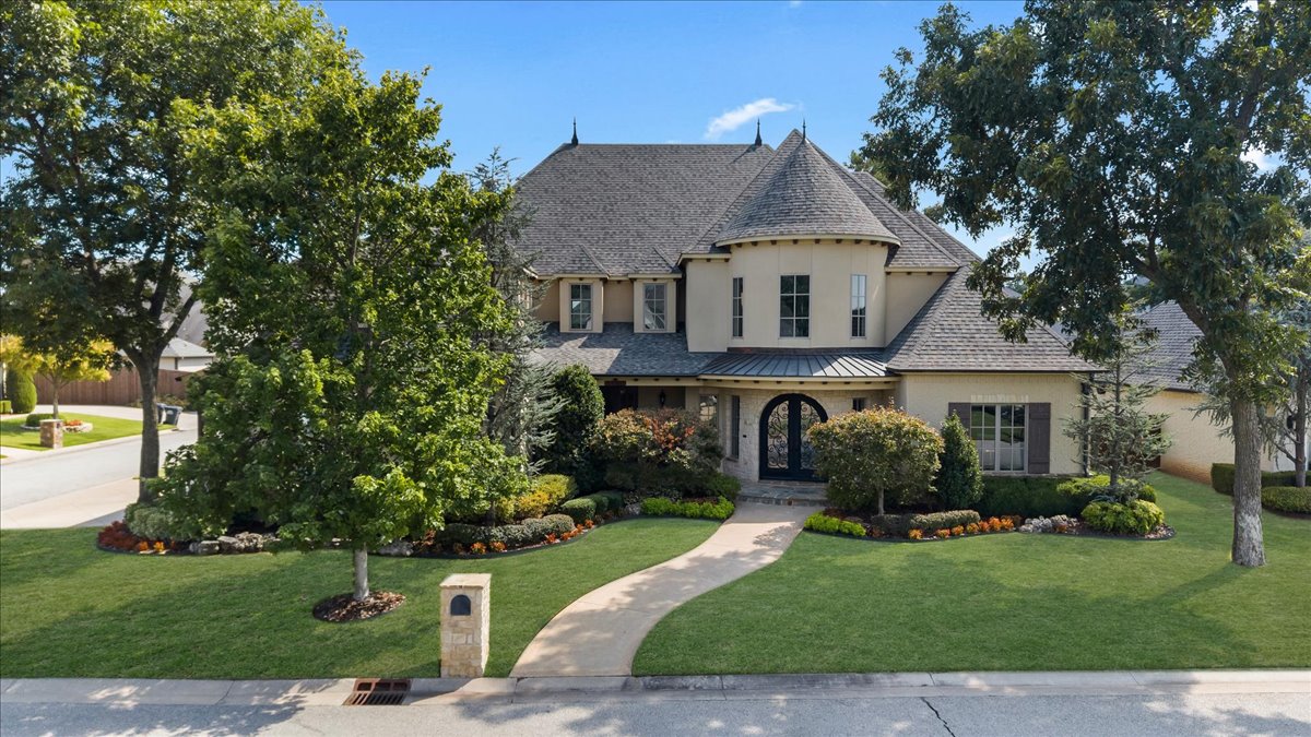 Two-story house with a turret, arched entry, landscaped lawn, and curved front walkway.