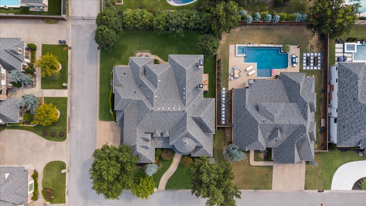 Aerial view of neighboring homes, with a backyard swimming pool beside one of the roofs.