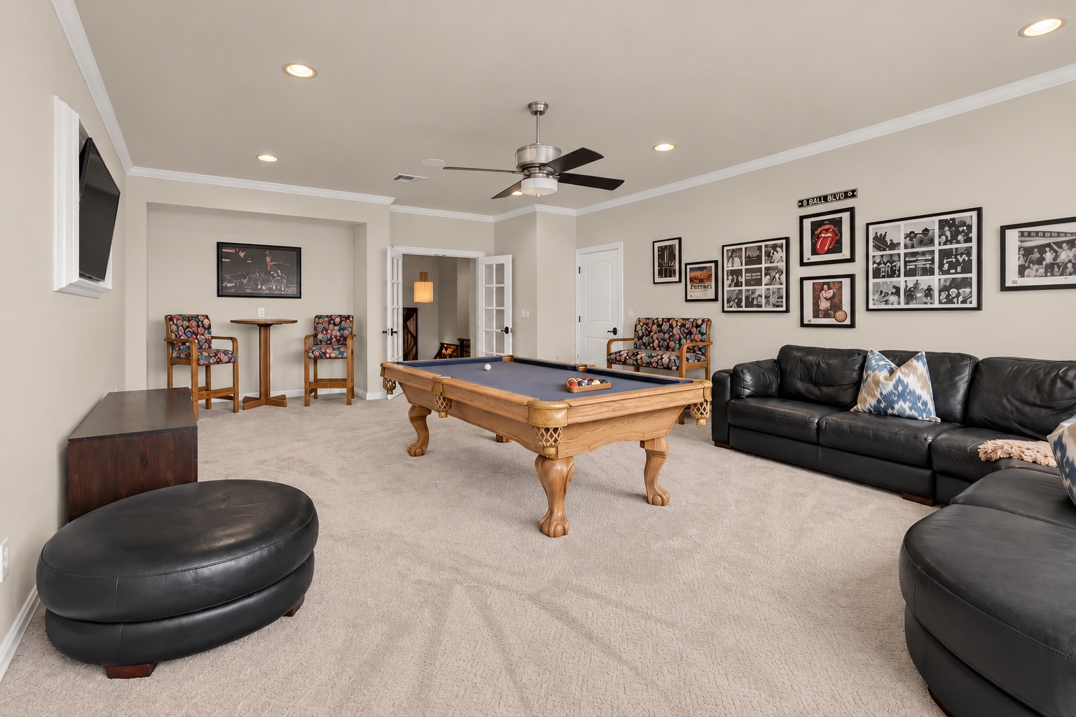 Game room with a pool table, black leather sectional, and framed sports memorabilia.