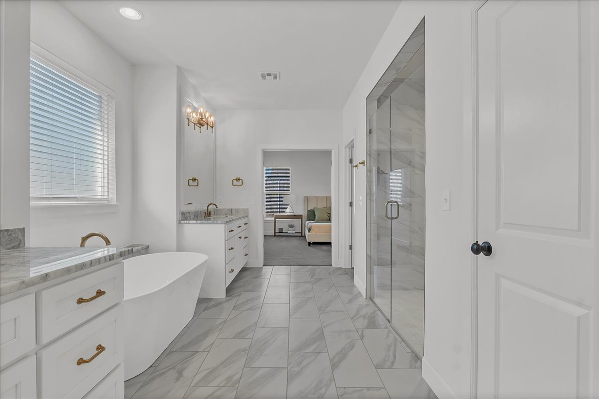 Primary bathroom with a freestanding soaking tub, double vanity, and glass-enclosed shower.