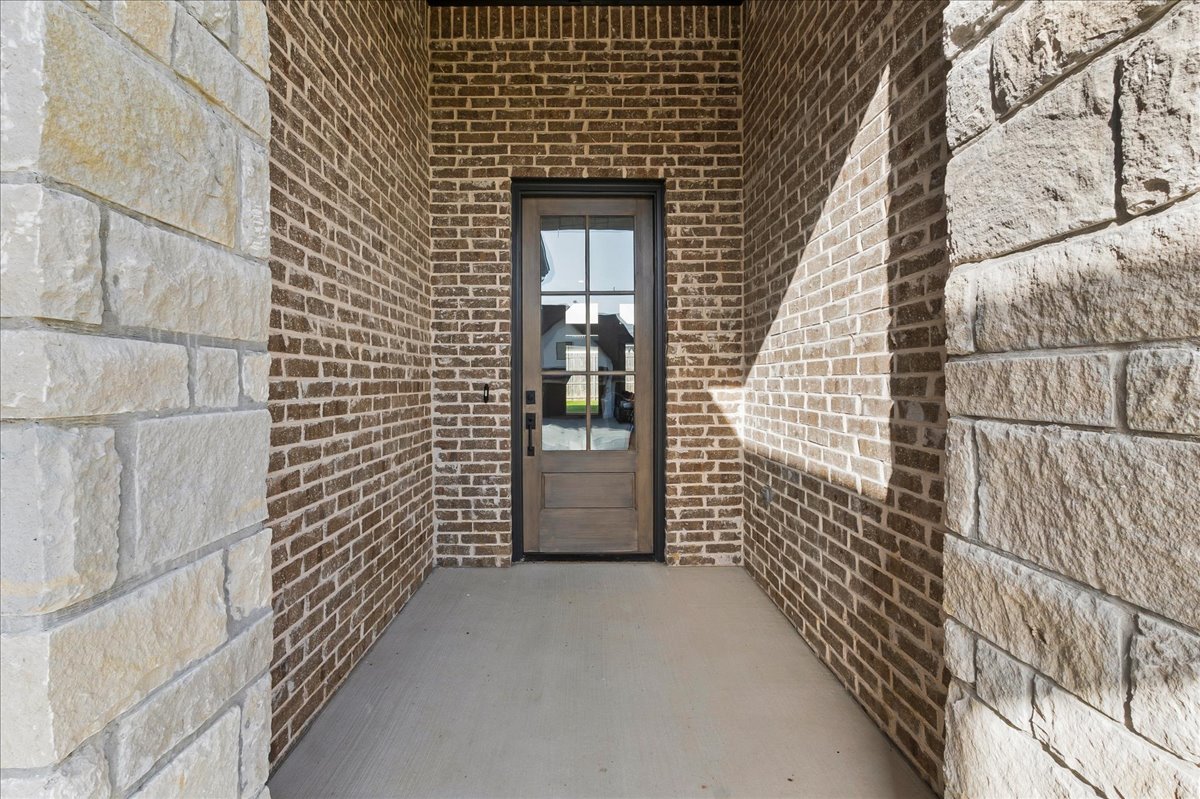 Brick-and-stone covered entry with a dark wood, glass-paneled front door.