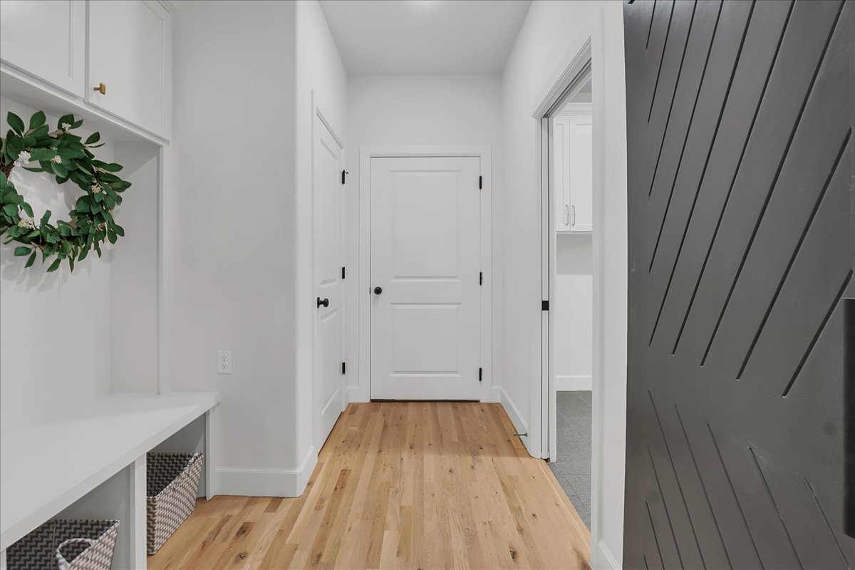 Bright entry hallway with built-in bench, wood flooring, and a dark gray front door.