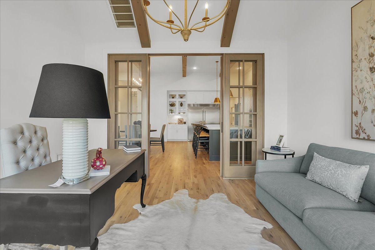 Living room with a gray sofa and white hide rug, opening through glass doors to the kitchen.