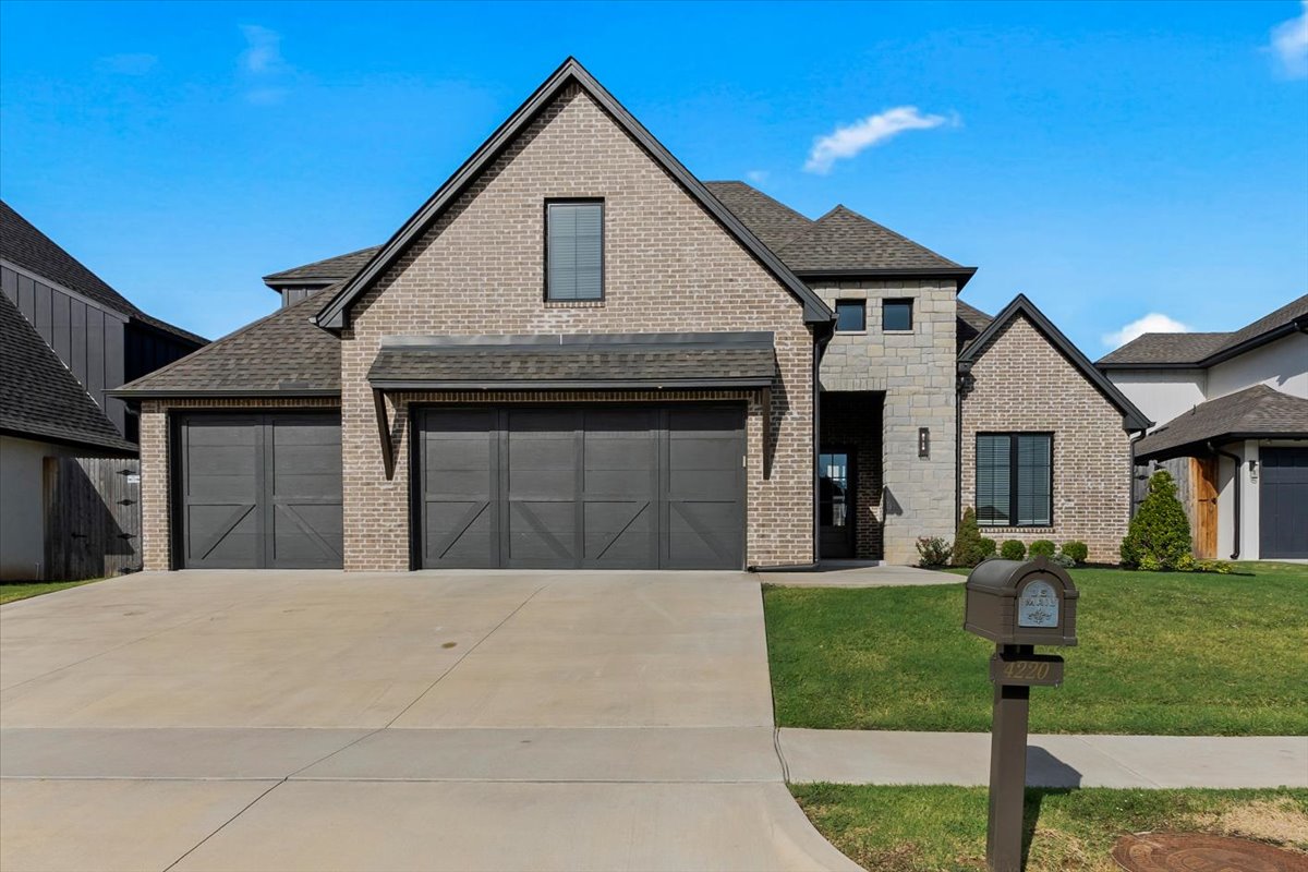 Brick-and-stone house with two dark garage doors, a wide driveway, and mailbox marked 4220.
