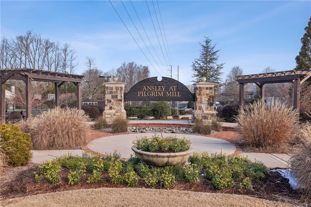 Ansley at Pilgrim Mill entrance sign framed by stone pillars and landscaped gardens.