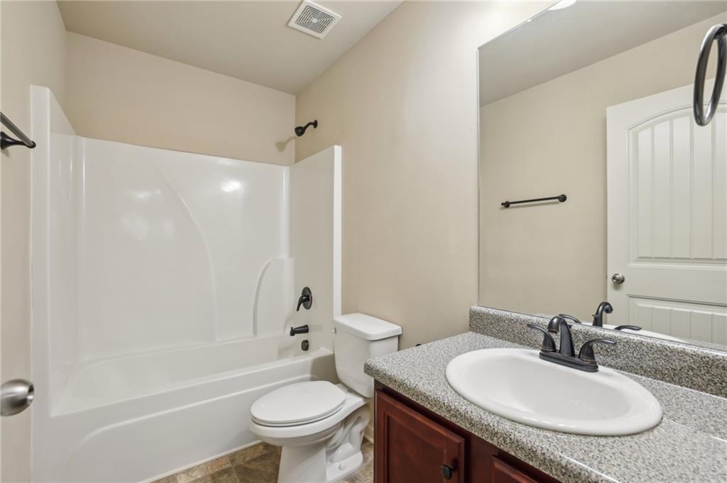Bathroom with a white tub and shower, toilet, and dark wood vanity.