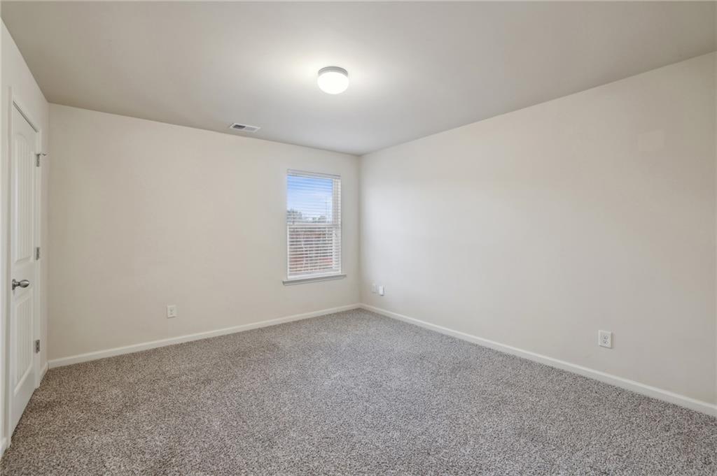 Empty carpeted room with a window and blinds.