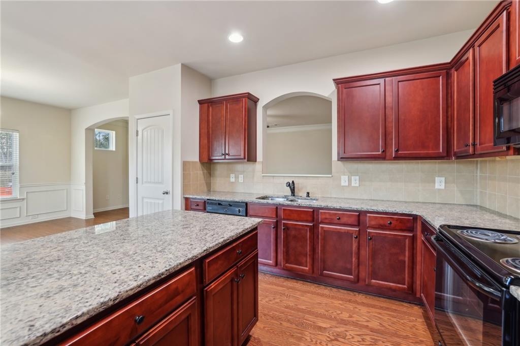 Kitchen with reddish wood cabinets, granite countertops, and a large island.