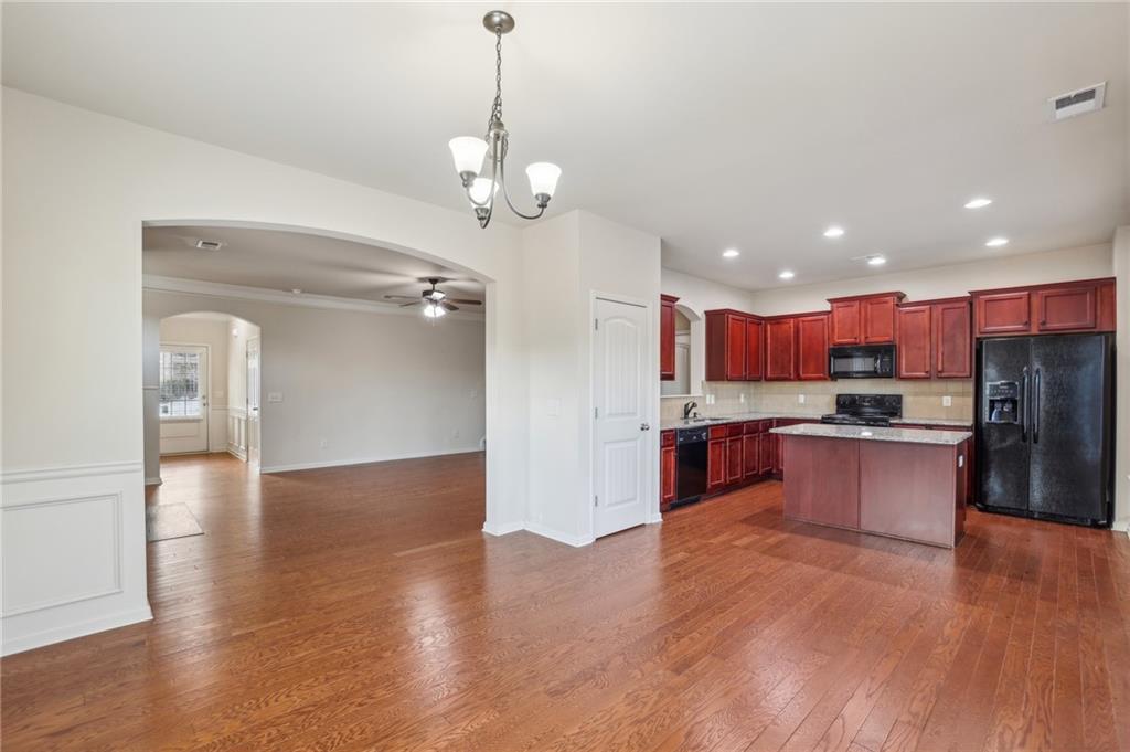 Open kitchen with a central island, reddish wood cabinets, and hardwood floors.