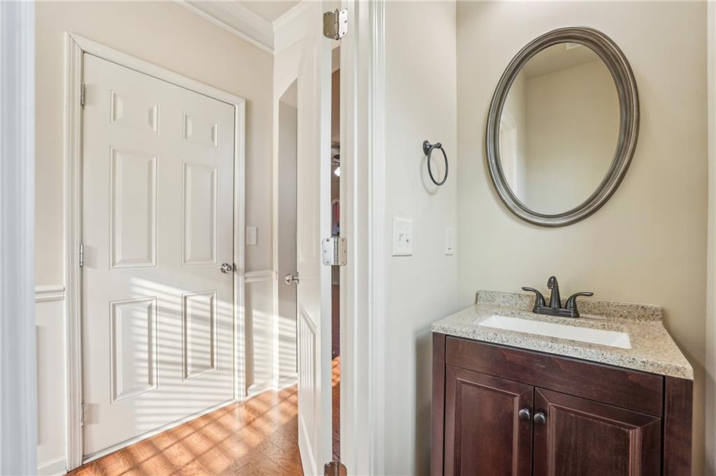 Bathroom vanity with a dark wood cabinet, stone countertop, and oval framed mirror beside a paneled door.
