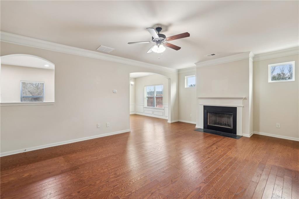 Empty living room with hardwood floors, a fireplace, and arched openings.