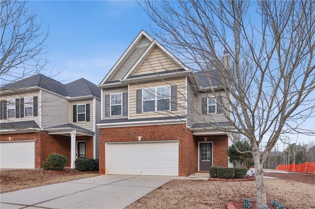 Two-story gray-and-brick house with a double garage and leafless trees in the front yard.