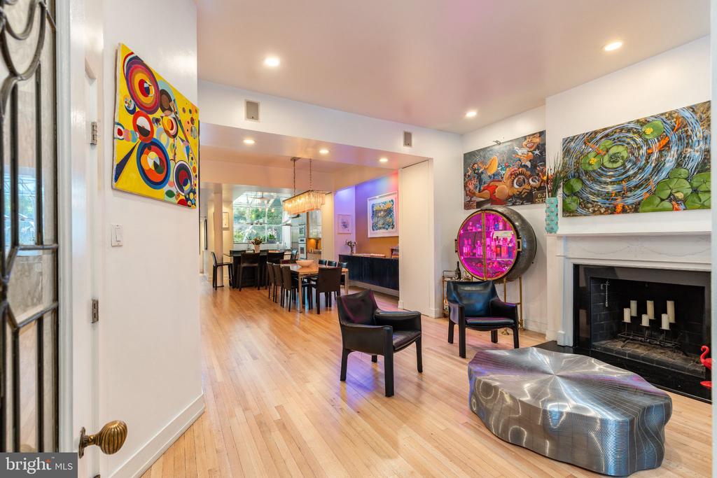 Open living and dining room with hardwood floors, a fireplace, and colorful artwork.