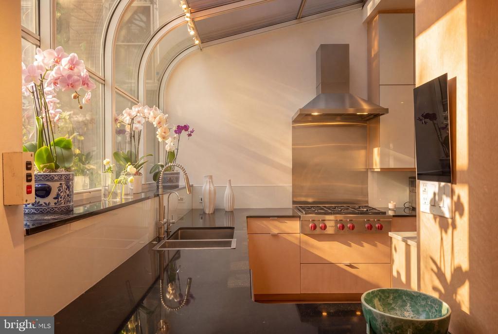 Kitchen with tall arched windows, pink orchids, and a stainless-steel range.