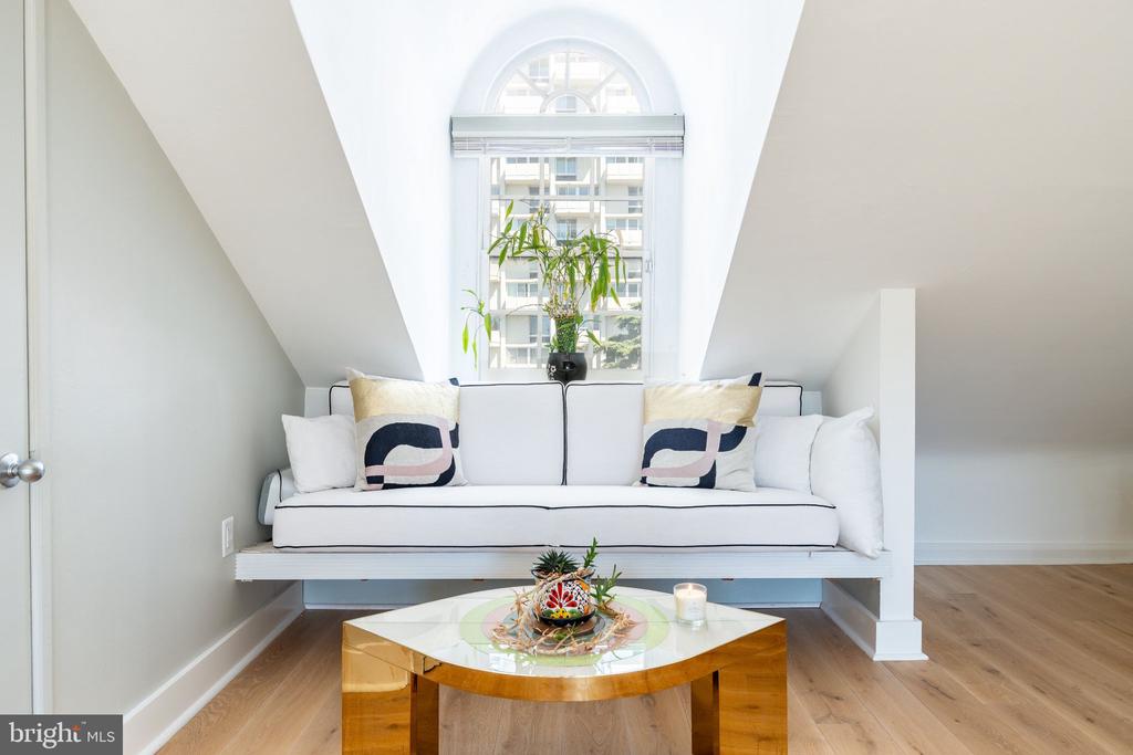 Living area with a built-in white window-seat sofa beneath an arched window and a gold coffee table.