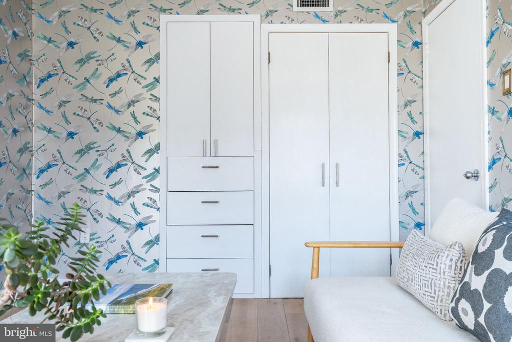 Furnished room with white built-in cabinets, a sofa, and blue dragonfly wallpaper.
