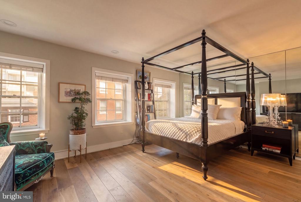 Bedroom with a dark four-poster bed, hardwood floors, and a green sitting area.