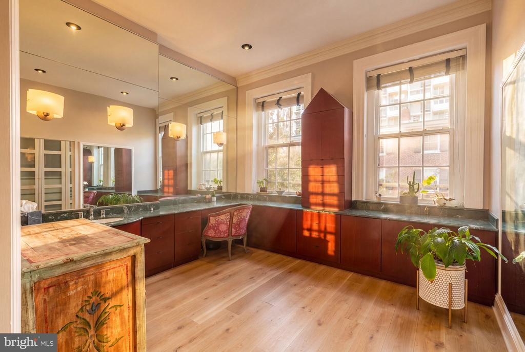Home office with mirrored walls, built-in wood cabinetry, and tall sunlit windows.