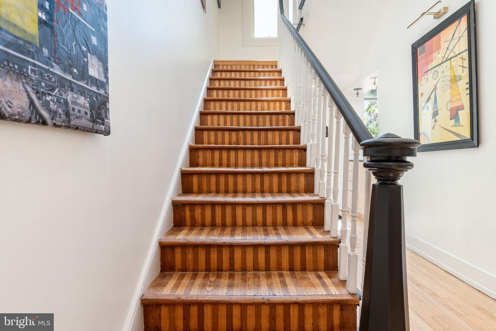 Wood staircase with white balusters, a dark handrail, and framed artwork.