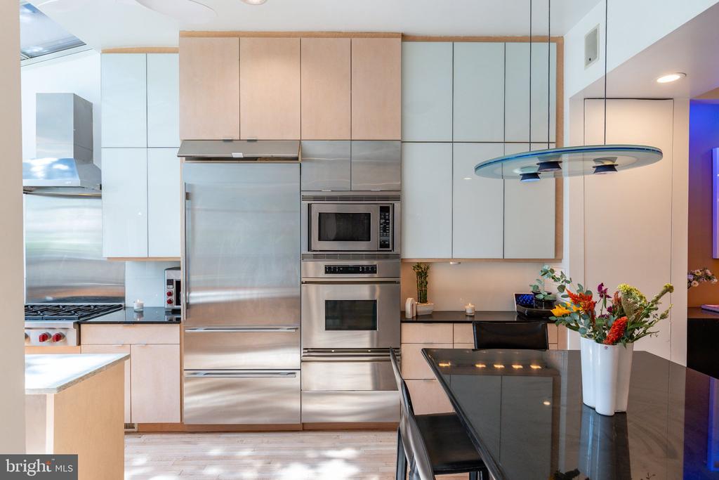 Modern kitchen with stainless steel appliances, pale cabinetry, and a black stone island.