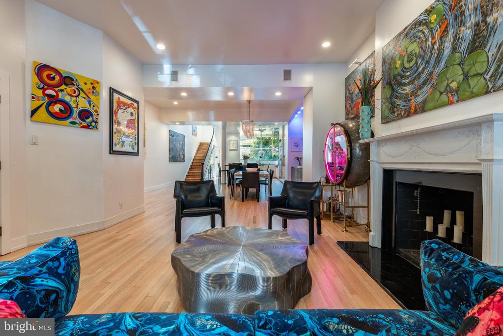 Living room with a white fireplace, colorful artwork, and an open dining area.
